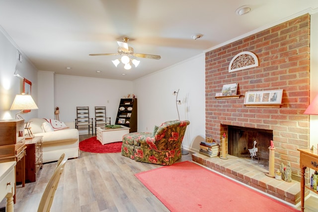 living room with crown molding, hardwood / wood-style floors, ceiling fan, and a brick fireplace