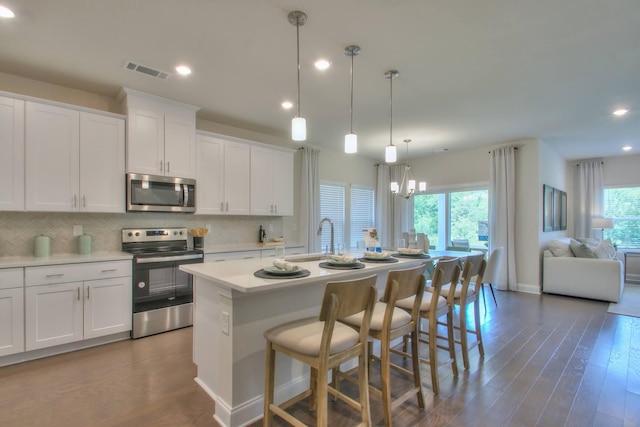 kitchen with a center island with sink, plenty of natural light, white cabinets, and stainless steel appliances