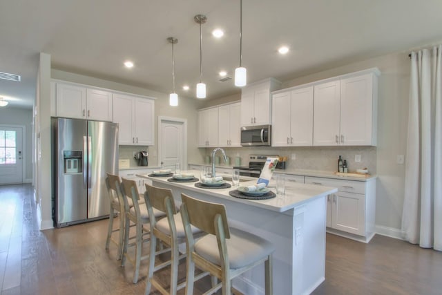 kitchen featuring white cabinets, appliances with stainless steel finishes, and pendant lighting