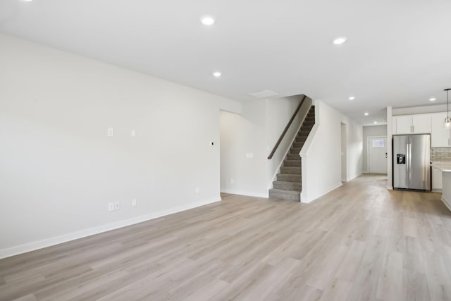 unfurnished living room with recessed lighting, light wood-style flooring, and stairs