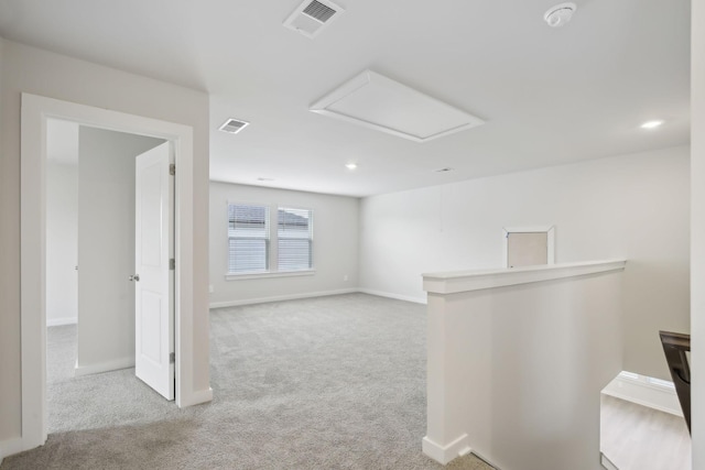 empty room with light carpet, visible vents, attic access, and baseboards