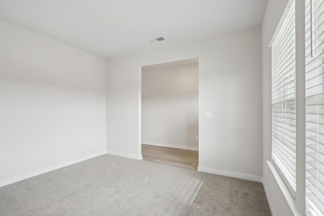 empty room with light carpet, visible vents, and baseboards