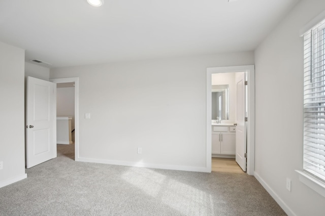 unfurnished bedroom with light carpet, baseboards, and multiple windows