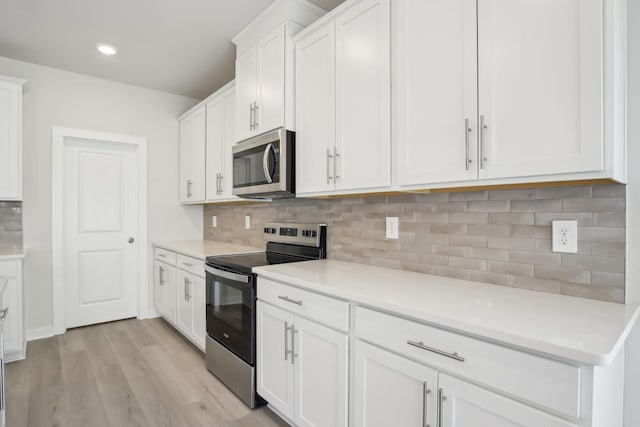 kitchen featuring stainless steel appliances, light countertops, backsplash, white cabinetry, and light wood-type flooring