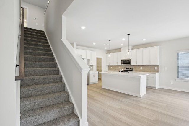 stairway with recessed lighting, baseboards, and wood finished floors