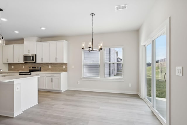 kitchen with stainless steel appliances, white cabinets, light countertops, and visible vents