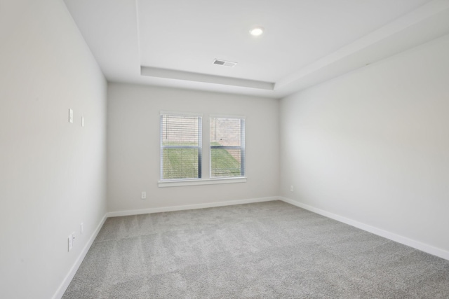 carpeted spare room featuring recessed lighting, a raised ceiling, and baseboards