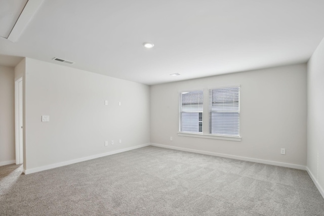 spare room featuring light colored carpet, visible vents, and baseboards