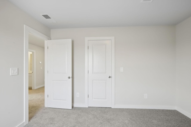 unfurnished bedroom with light carpet, visible vents, and baseboards