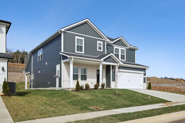 view of front of house featuring board and batten siding, a front yard, brick siding, and a garage