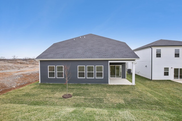 back of house with a yard, a shingled roof, and a patio area