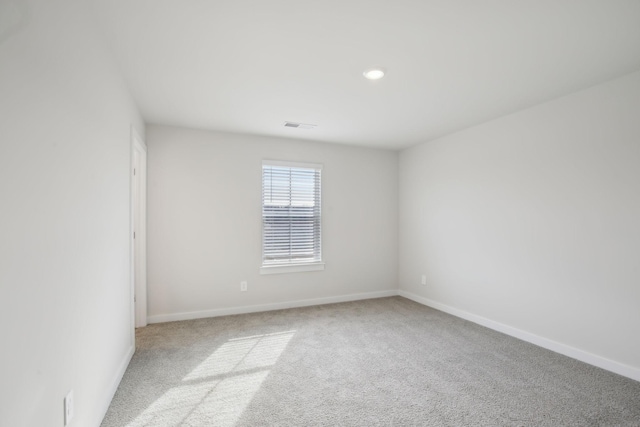 empty room featuring light carpet, visible vents, and baseboards