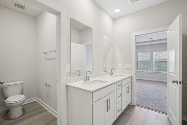 bathroom featuring double vanity, a sink, toilet, and baseboards