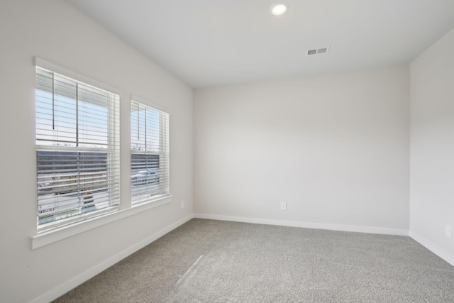 carpeted empty room with baseboards, visible vents, and recessed lighting