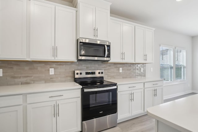 kitchen featuring light wood finished floors, appliances with stainless steel finishes, light countertops, white cabinetry, and backsplash