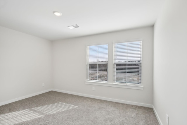 carpeted spare room with visible vents and baseboards