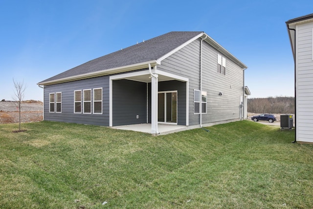 rear view of property featuring a patio area, cooling unit, a lawn, and roof with shingles