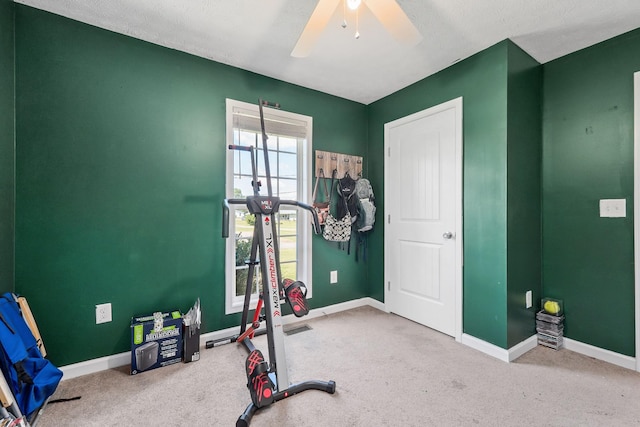 exercise area featuring ceiling fan, carpet, and a textured ceiling