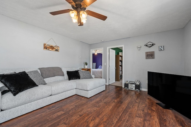 living room featuring a textured ceiling, ceiling fan, and dark wood-type flooring