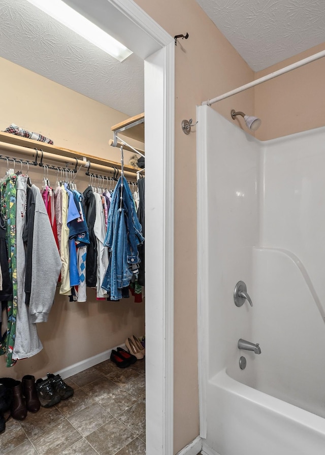 bathroom with a textured ceiling and  shower combination