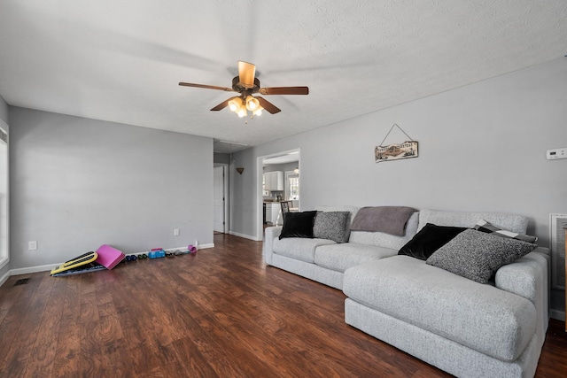 living room featuring ceiling fan, dark hardwood / wood-style flooring, and a textured ceiling