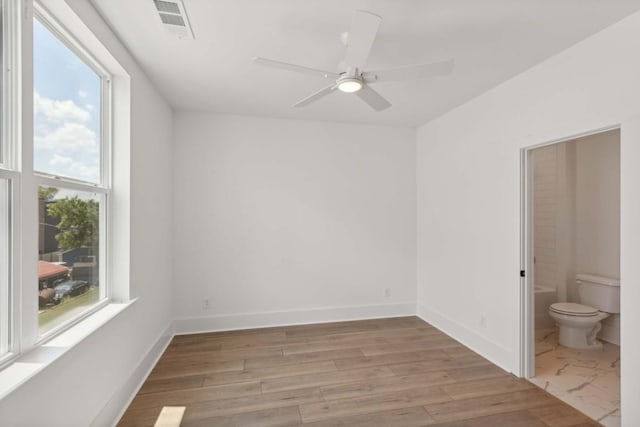 empty room with ceiling fan, plenty of natural light, and light wood-type flooring