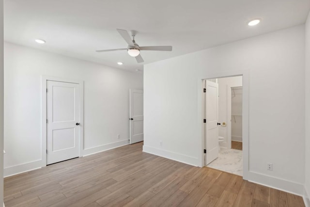 unfurnished bedroom with ceiling fan, a closet, light wood-type flooring, and ensuite bath