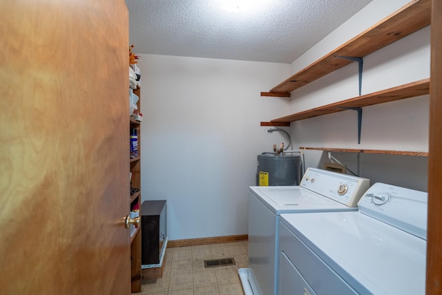 washroom with washer and dryer, a textured ceiling, and water heater