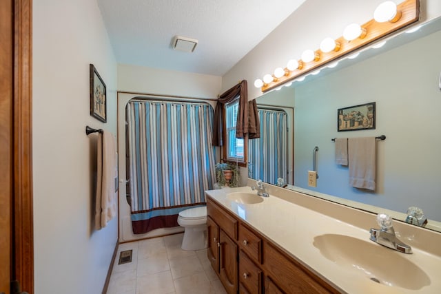 bathroom with tile patterned floors, vanity, a textured ceiling, and toilet