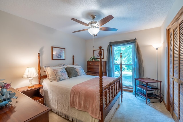 carpeted bedroom with ceiling fan, a textured ceiling, and a closet