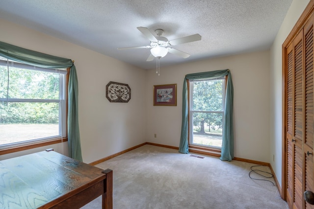 unfurnished office featuring a textured ceiling, light colored carpet, and ceiling fan