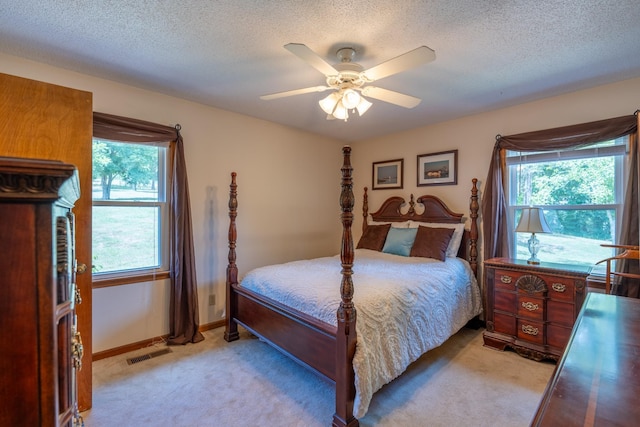 carpeted bedroom with ceiling fan and a textured ceiling