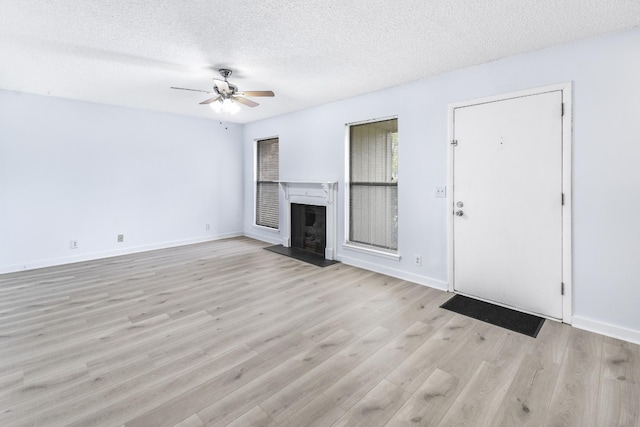 unfurnished living room with ceiling fan, a textured ceiling, and light wood-type flooring