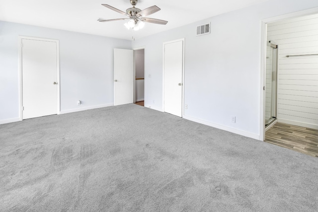 unfurnished bedroom with connected bathroom, dark carpet, and ceiling fan