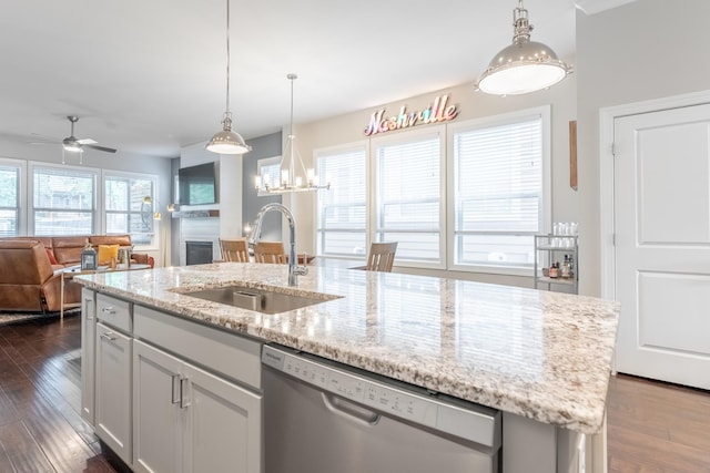 kitchen with an island with sink, dark hardwood / wood-style floors, stainless steel dishwasher, and sink