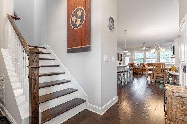 stairs with ceiling fan with notable chandelier and wood-type flooring