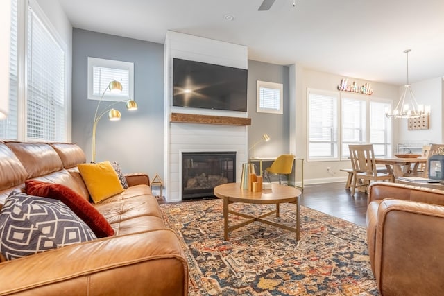 living room with a large fireplace, ceiling fan with notable chandelier, and dark hardwood / wood-style floors