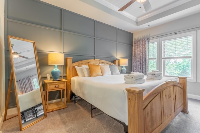 bedroom with a raised ceiling, ceiling fan, crown molding, and light colored carpet