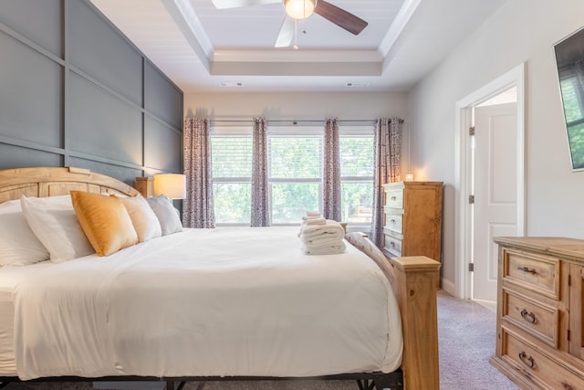 carpeted bedroom featuring a raised ceiling and ceiling fan