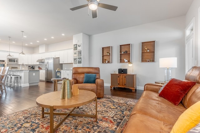 living room with ceiling fan, sink, and dark wood-type flooring