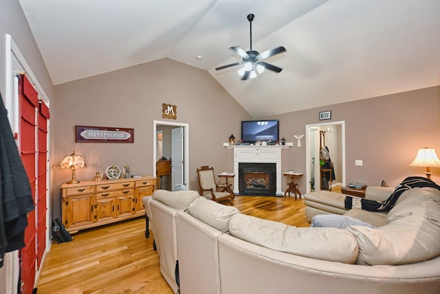 living room featuring ceiling fan, light wood-type flooring, and vaulted ceiling