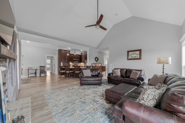 living room with a brick fireplace, high vaulted ceiling, light hardwood / wood-style flooring, and ceiling fan