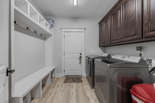 laundry area featuring washer and clothes dryer, cabinets, and light wood-type flooring