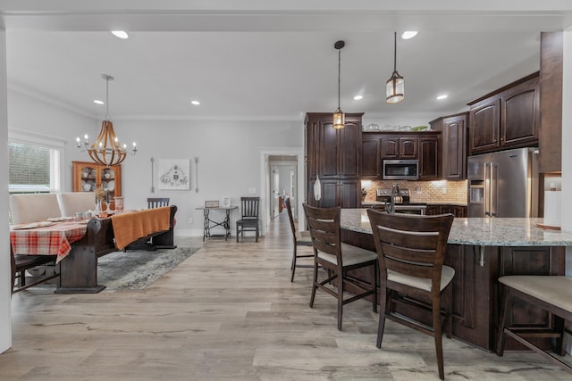 kitchen featuring light hardwood / wood-style floors, dark brown cabinetry, stainless steel appliances, and hanging light fixtures