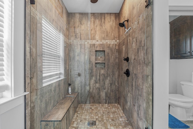 bathroom featuring a tile shower and toilet