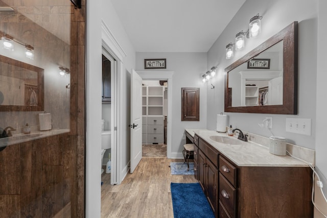 bathroom with hardwood / wood-style floors, vanity, toilet, and a shower