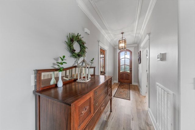 entryway with crown molding, light hardwood / wood-style floors, and a notable chandelier