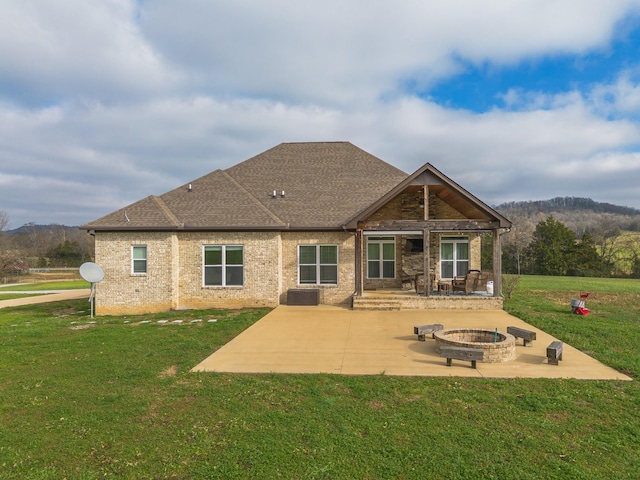 back of property with a yard, a fire pit, and a patio area