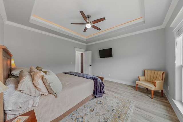 bedroom with a raised ceiling, ceiling fan, crown molding, and light wood-type flooring