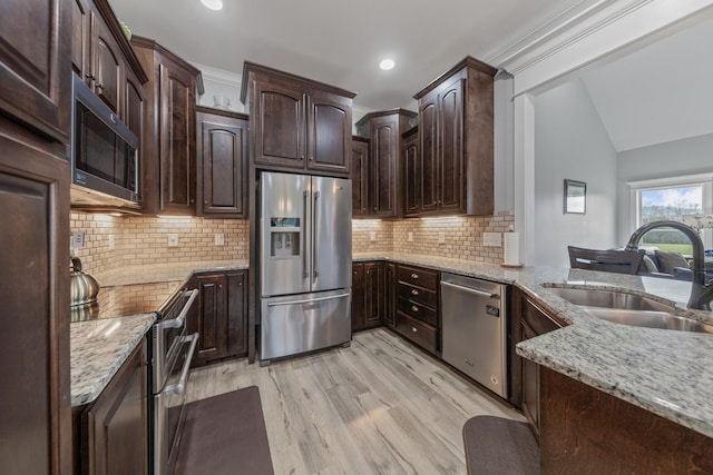 kitchen with appliances with stainless steel finishes, backsplash, dark brown cabinetry, sink, and light hardwood / wood-style floors